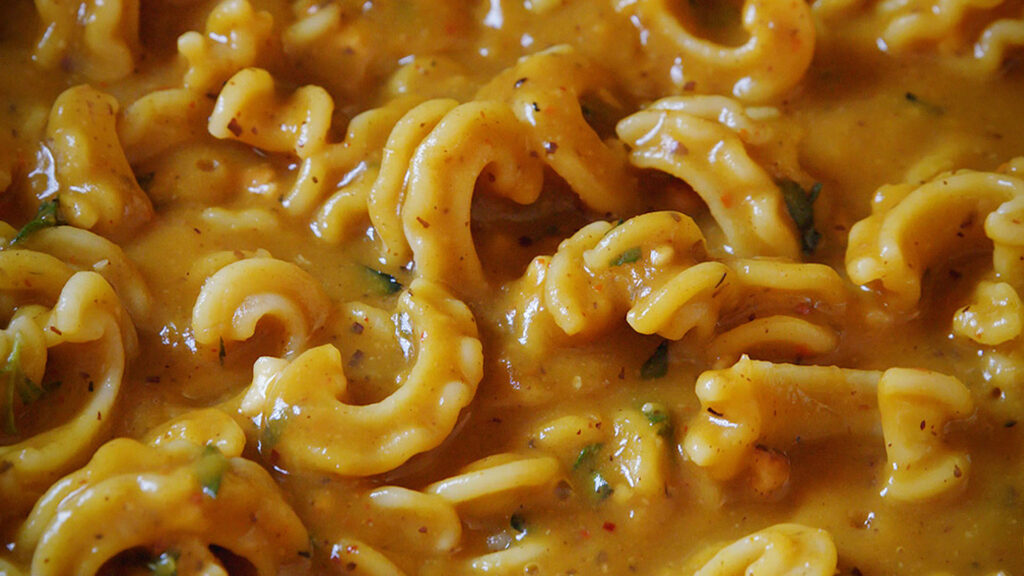 a pan full of pasta in a rich looking pumpkin sauce with herbs and spices