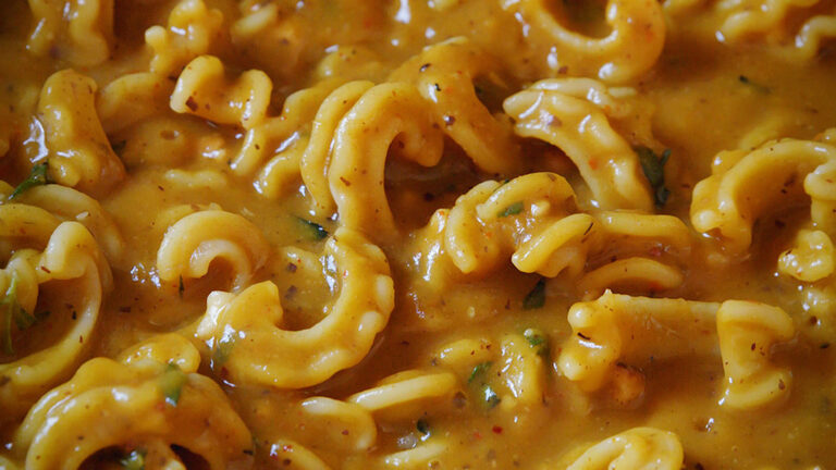 a pan full of pasta in a rich looking pumpkin sauce with herbs and spices