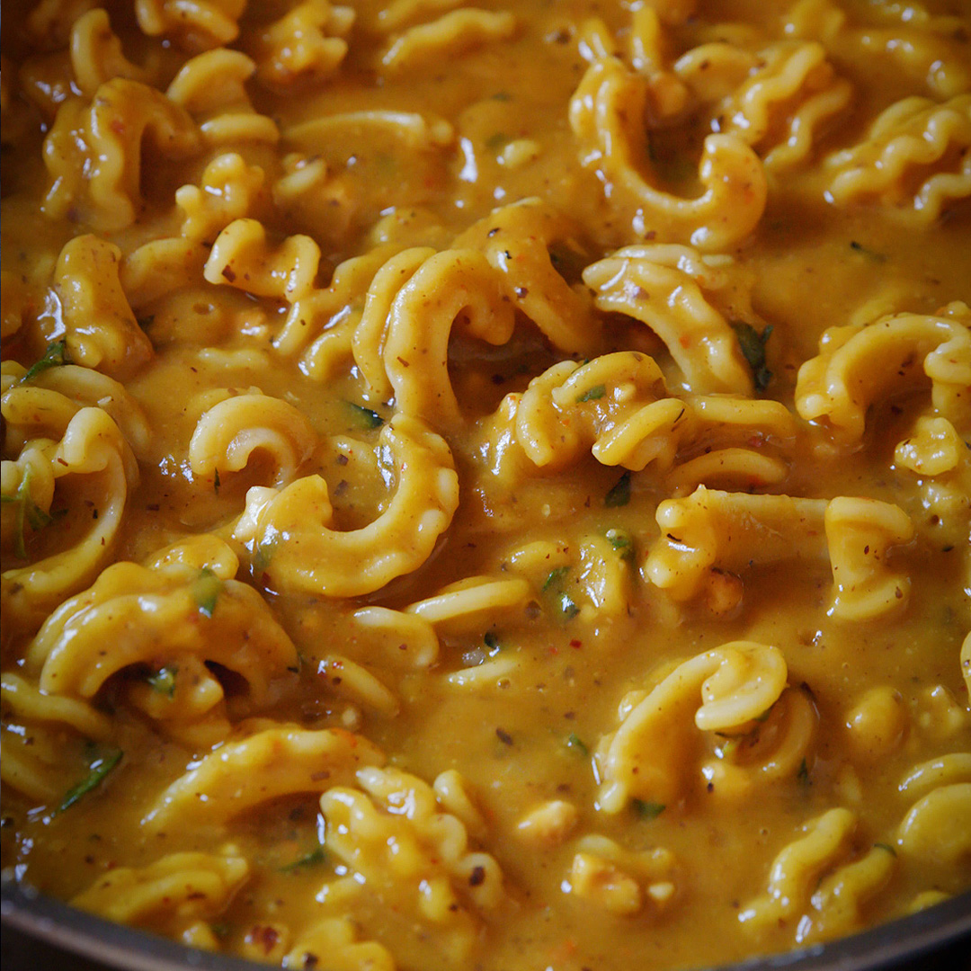 a pan full of pasta in a rich looking pumpkin sauce with herbs and spices