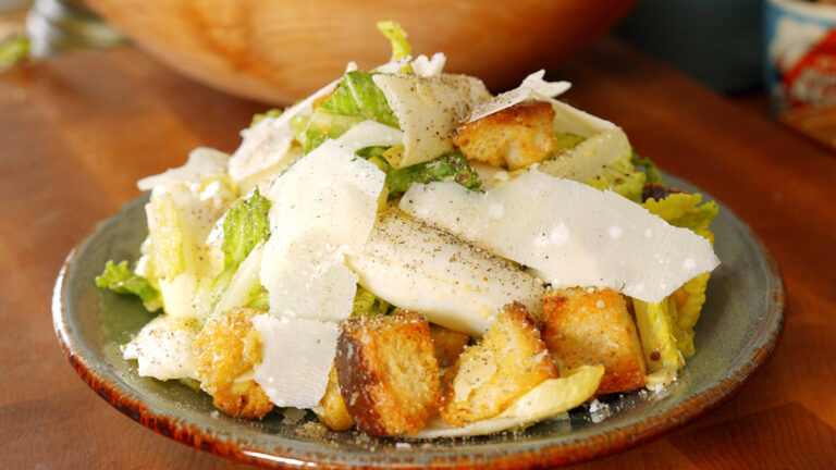 a plate full of caesar salad with big shavings of parmesan cheese