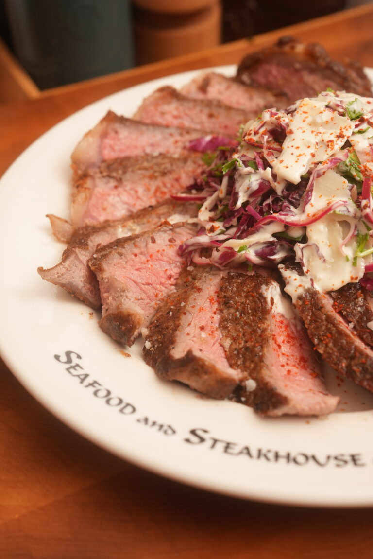 a perfectly cooked steak dinner on a plate with a bitter green salad and dressing.