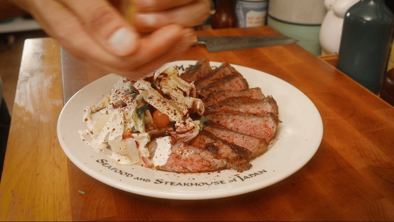 an animation of plating a perfectly cooked steak dinner on a plate with a bitter green salad and dressing.