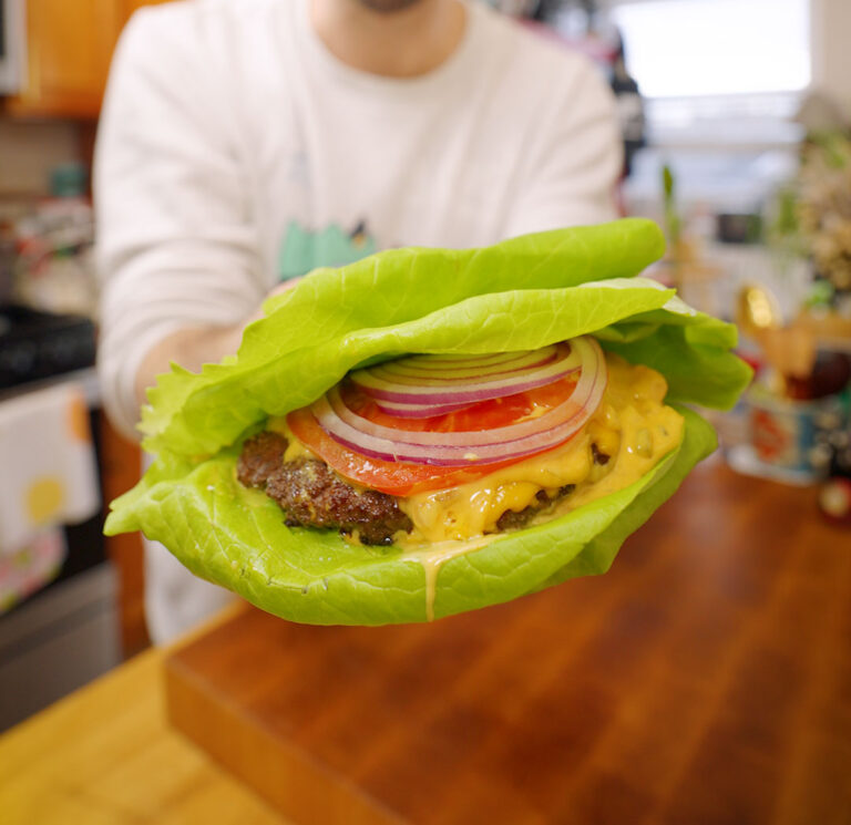 a smash burger with cheese, tomato, red onion and big mac sauce in a lettuce wrap