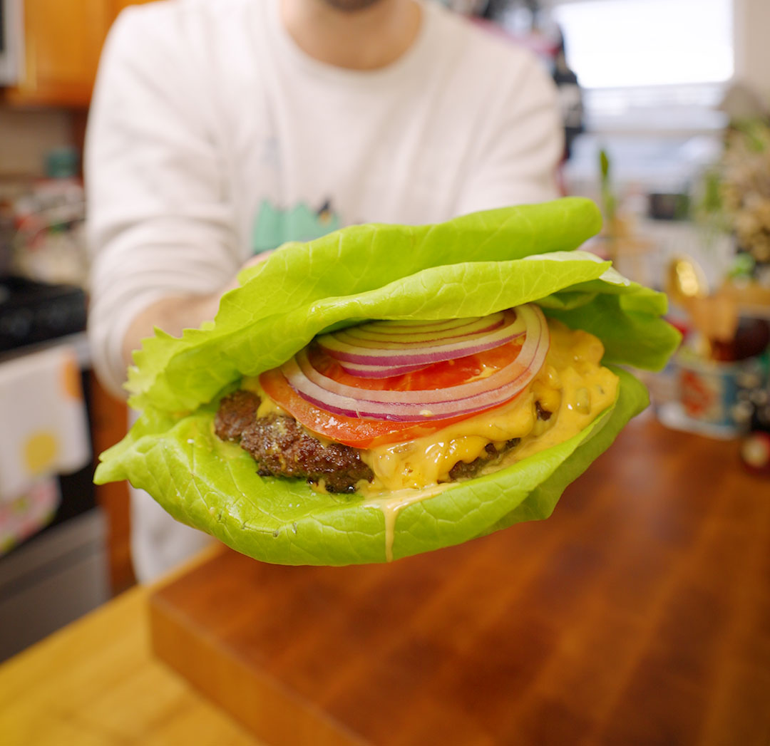 a smash burger with cheese, tomato, red onion and big mac sauce in a lettuce wrap