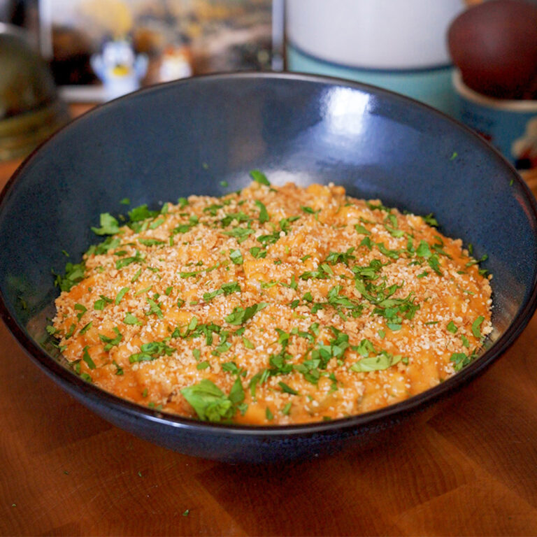 a big bowl of mac and cheese with herbs and toasted breadcrumbs