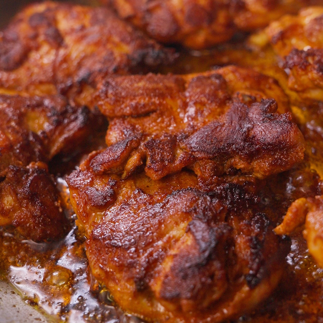 Paprika-marinated chicken thighs seared until deeply browned and lightly charred in a skillet.