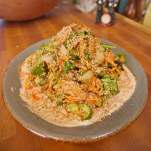 Kimchi cucumber tuna salad with carrots, fresh herbs, sesame seeds, and creamy yogurt sauce on a plate.